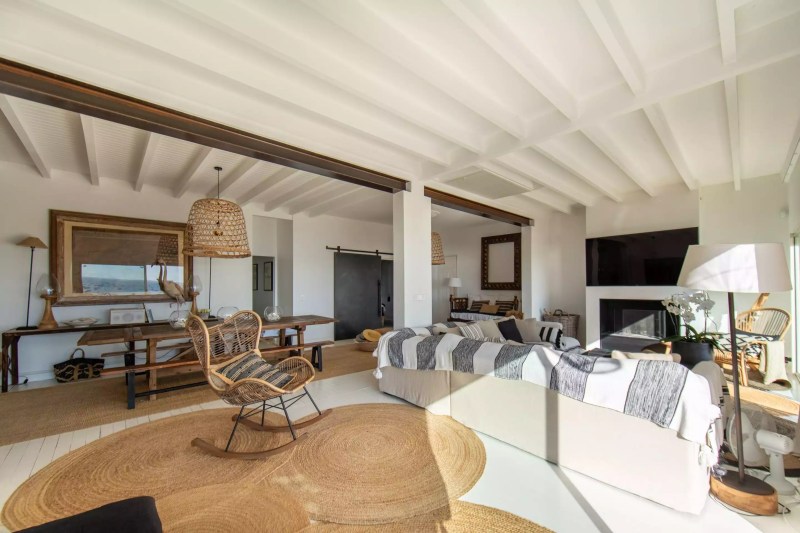 Intérieur lumineux et moderne de la Villa Biancasa, avec un salon confortable, des meubles en rotin, un tapis rond, et des éléments décoratifs naturels.